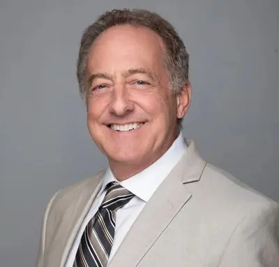 A man in a suit and tie smiling for the camera.