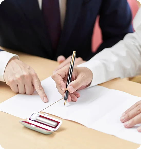 Person signing a document with a pen.