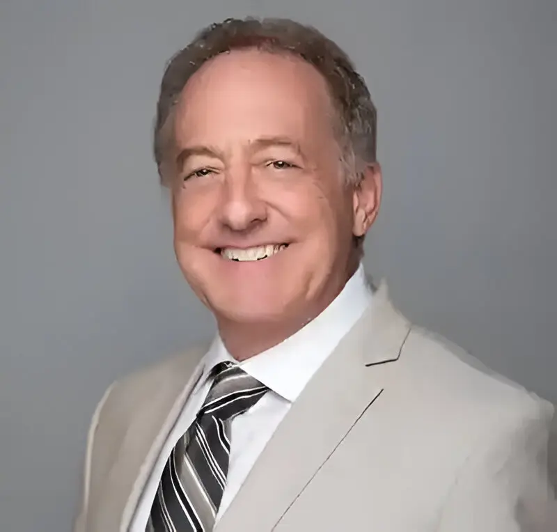 Smiling man in tan suit and tie.