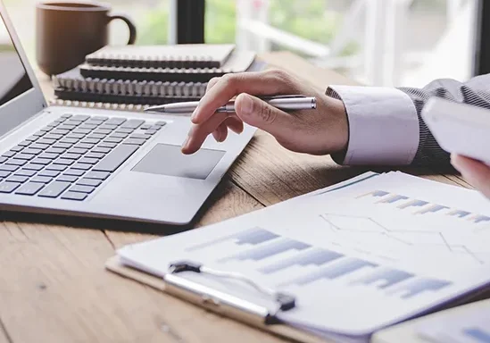 Person working on laptop with financial charts.